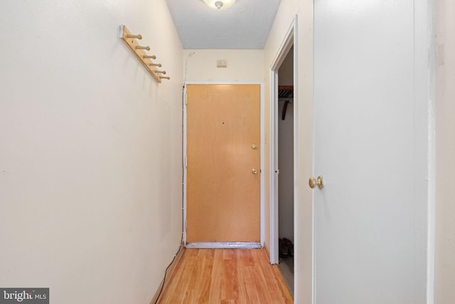 corridor featuring light wood-type flooring and a textured ceiling