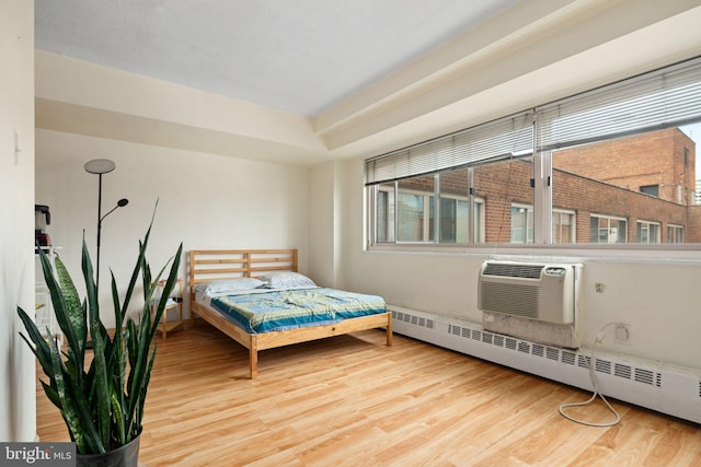 bedroom with wood-type flooring, baseboard heating, and a wall mounted air conditioner