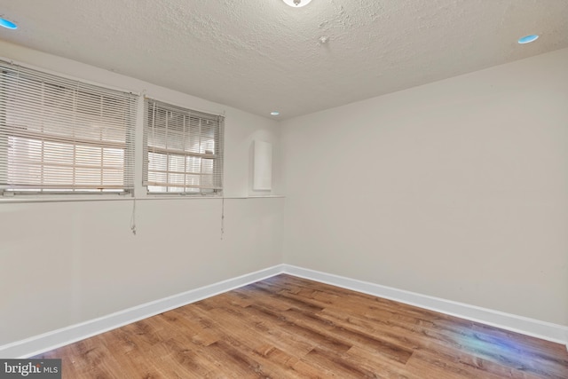 unfurnished room featuring wood-type flooring and a textured ceiling