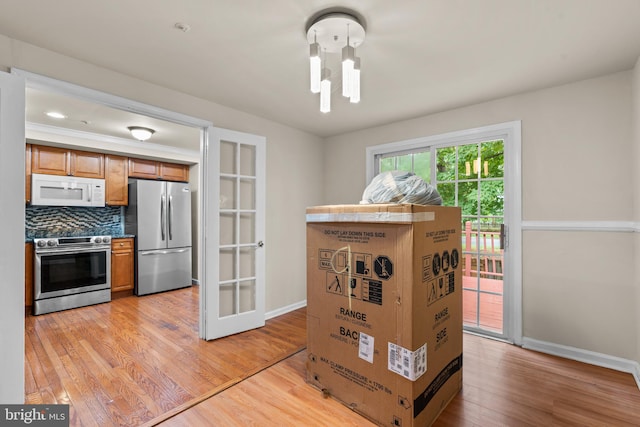 kitchen with decorative backsplash, light wood-type flooring, stainless steel appliances, and french doors