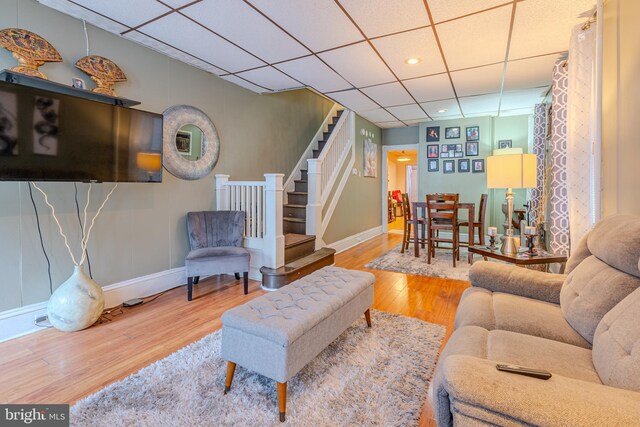 living room with a drop ceiling and wood-type flooring