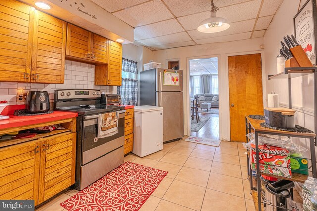 kitchen featuring a paneled ceiling, stainless steel appliances, light hardwood / wood-style flooring, decorative backsplash, and decorative light fixtures