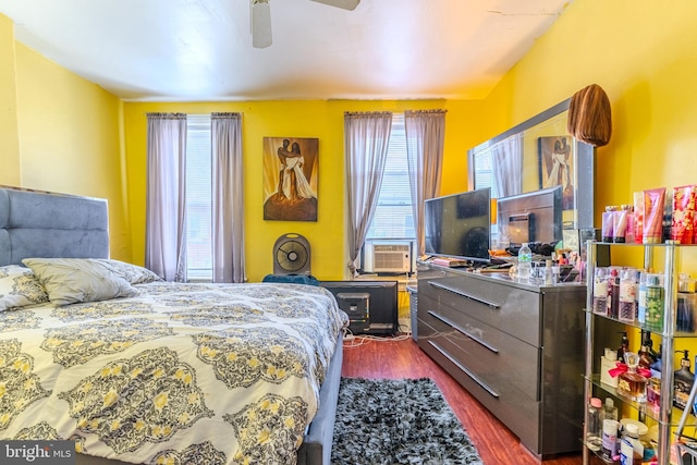 bedroom featuring ceiling fan, dark hardwood / wood-style flooring, multiple windows, and cooling unit