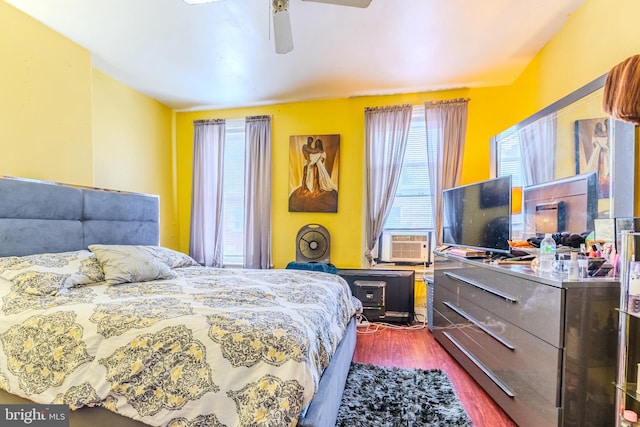 bedroom featuring ceiling fan, hardwood / wood-style flooring, multiple windows, and cooling unit