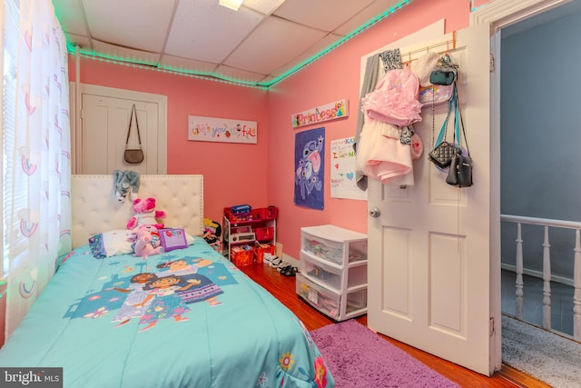 bedroom with a drop ceiling and hardwood / wood-style flooring