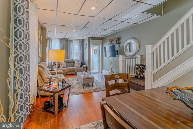 living room with a paneled ceiling and wood-type flooring