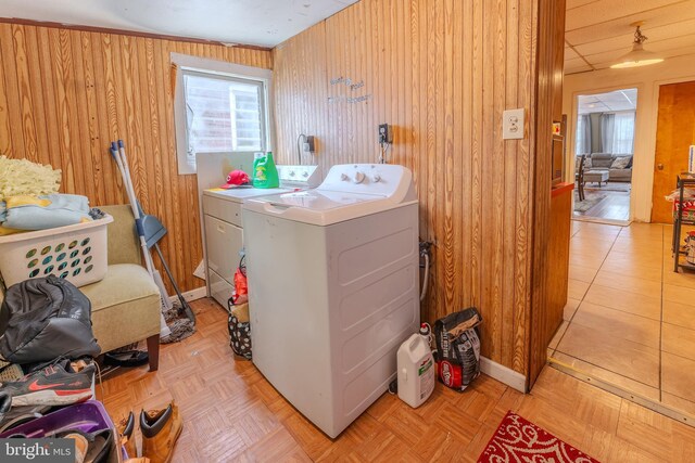 washroom with washer and dryer, light parquet floors, and wooden walls