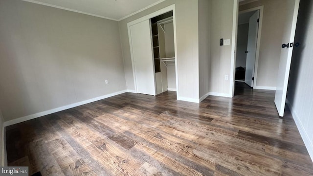 unfurnished bedroom featuring ornamental molding, dark wood-type flooring, and a closet