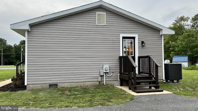 view of property exterior with a lawn and cooling unit