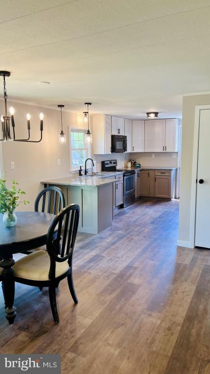 kitchen with pendant lighting, electric range, hardwood / wood-style flooring, white cabinetry, and kitchen peninsula