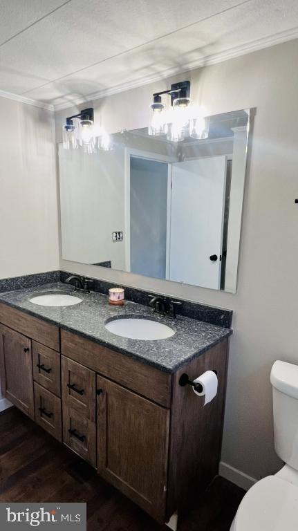 bathroom with crown molding, hardwood / wood-style floors, vanity, and toilet