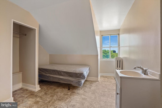 bedroom featuring a closet, light tile patterned floors, sink, and lofted ceiling