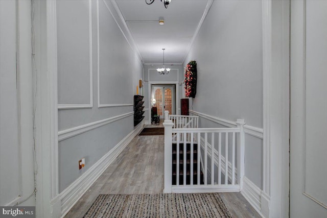 corridor featuring an inviting chandelier, ornamental molding, and hardwood / wood-style flooring