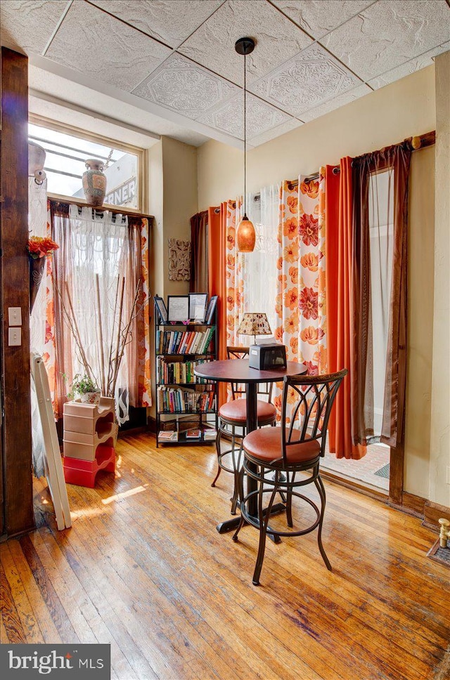 dining room with light wood-type flooring and a drop ceiling