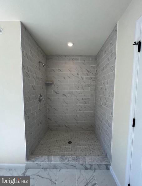 bathroom featuring marble finish floor and a stall shower