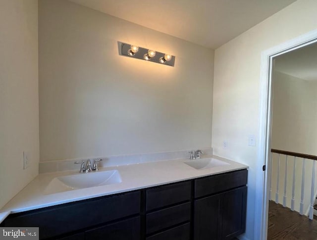 bathroom with double vanity, wood finished floors, and a sink