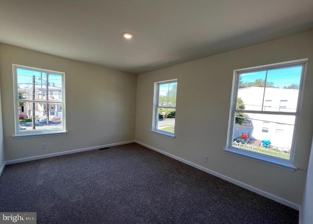 empty room featuring visible vents, recessed lighting, baseboards, and dark colored carpet