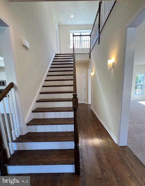 stairs with baseboards, a towering ceiling, and wood finished floors