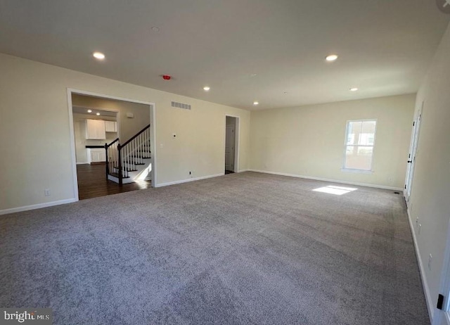 spare room featuring visible vents, baseboards, stairway, recessed lighting, and dark colored carpet