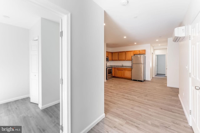 kitchen featuring light hardwood / wood-style flooring, stainless steel appliances, and an AC wall unit