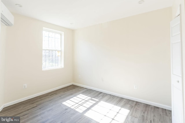 empty room with light hardwood / wood-style flooring and a wall unit AC