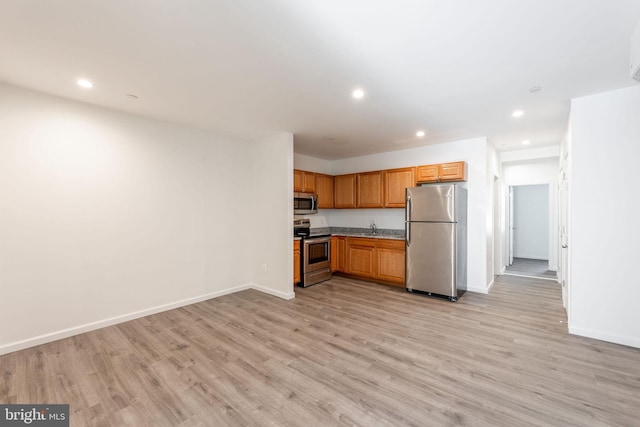 kitchen with light wood-type flooring, appliances with stainless steel finishes, and sink