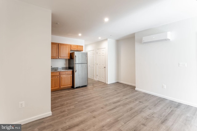 kitchen with stainless steel refrigerator, light hardwood / wood-style flooring, and a wall unit AC