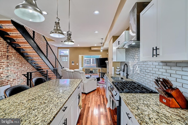 kitchen with sink, light stone countertops, stainless steel range with gas stovetop, and white cabinets