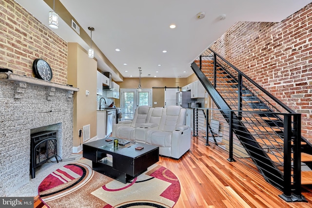 living room featuring brick wall, sink, and light hardwood / wood-style flooring