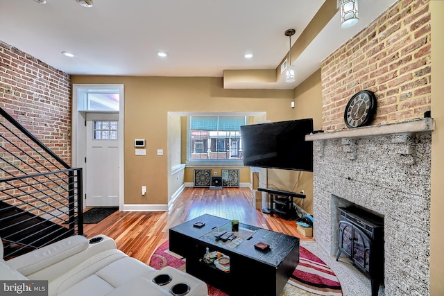 living room with a large fireplace, brick wall, and hardwood / wood-style floors