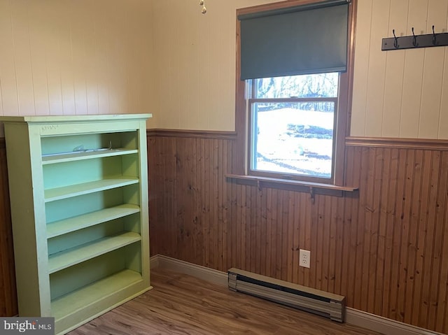 interior space with wood walls, hardwood / wood-style floors, and a baseboard heating unit