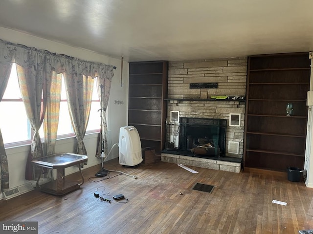 living room with wood-type flooring and a stone fireplace