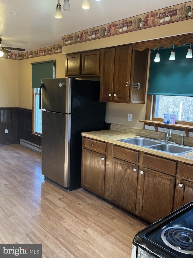 kitchen featuring ceiling fan, sink, range, light hardwood / wood-style floors, and stainless steel refrigerator