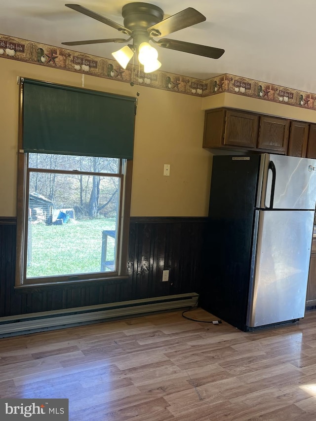 kitchen with ceiling fan, a baseboard heating unit, stainless steel refrigerator, and light hardwood / wood-style flooring