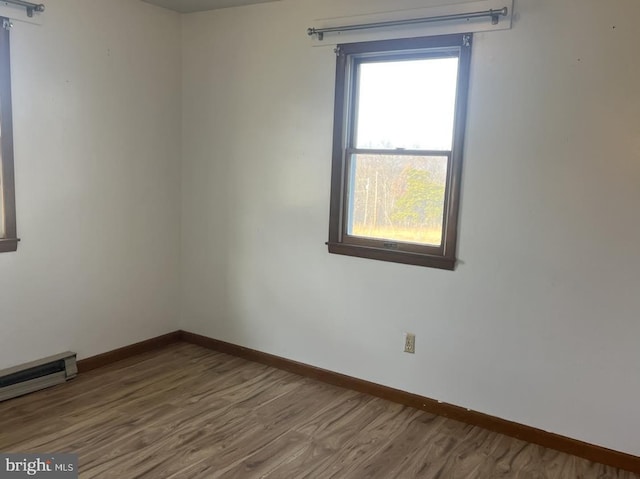 empty room featuring hardwood / wood-style floors and a baseboard heating unit