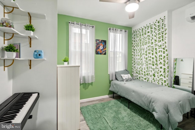 bedroom with light hardwood / wood-style flooring, a wall mounted air conditioner, and ceiling fan