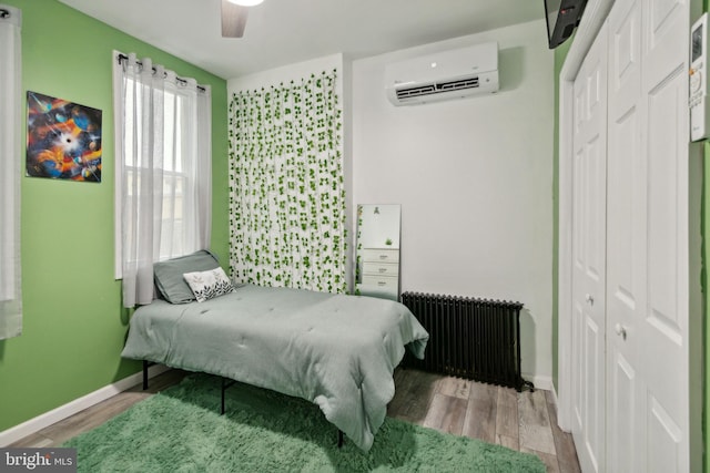 bedroom featuring ceiling fan, wood-type flooring, radiator, and a closet