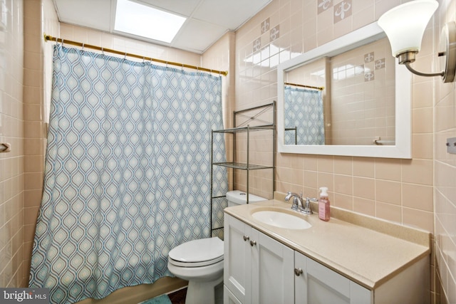 bathroom with tasteful backsplash, vanity, tile walls, and toilet