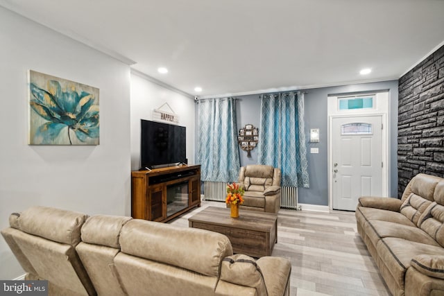 living room featuring light wood-type flooring, ornamental molding, and radiator heating unit