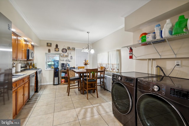 laundry area with a notable chandelier, light tile patterned floors, washing machine and dryer, and a healthy amount of sunlight