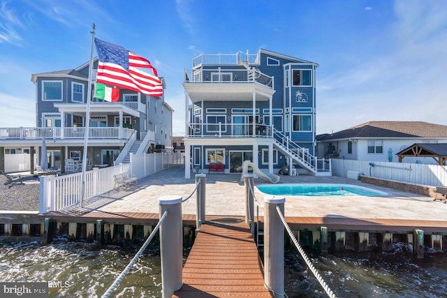 rear view of property featuring a patio, a balcony, and a water view