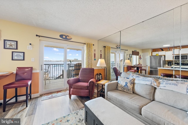 living room featuring a water view, a textured ceiling, and light wood-type flooring