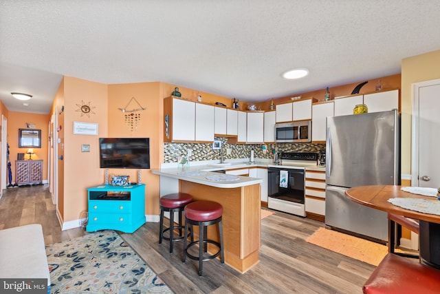 500 32nd St Unit A, Ocean City, MD 21842 - kitchen featuring stainless steel appliances, a peninsula, backsplash, light wood-style flooring, and a textured ceiling