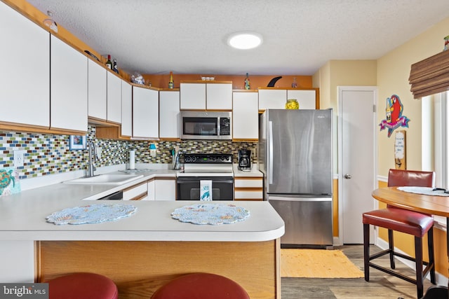 500 32nd St Unit A, Ocean City, MD 21842 - kitchen featuring appliances with stainless steel finishes, a sink, light countertops, a peninsula, and a textured ceiling
