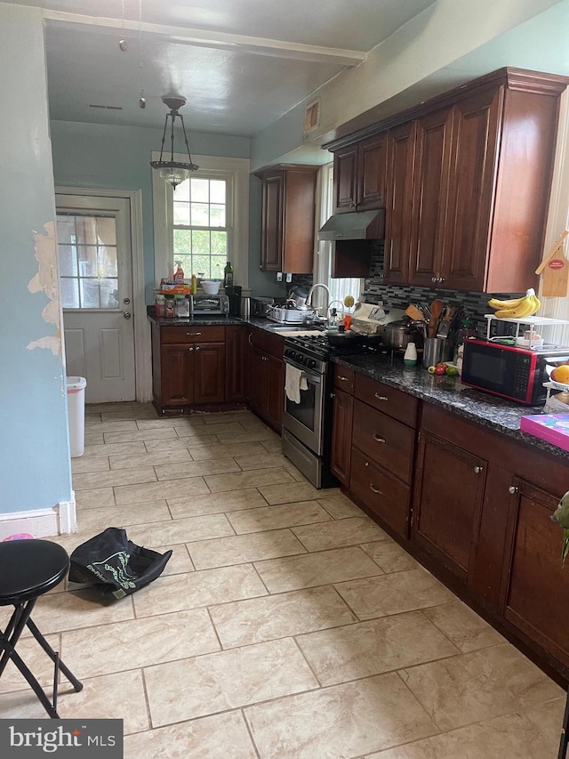 kitchen featuring decorative backsplash, pendant lighting, dark brown cabinets, stainless steel range with gas stovetop, and dark stone counters