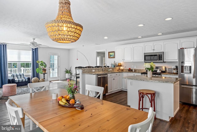 dining room with ceiling fan, a textured ceiling, sink, and wood-type flooring