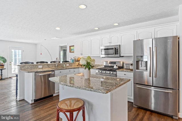 kitchen with stone countertops, a center island, dark wood-type flooring, and stainless steel appliances