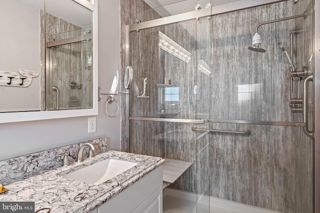 bathroom featuring a shower with shower door and vanity