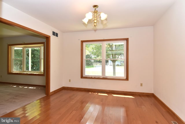 unfurnished room featuring light wood-type flooring and an inviting chandelier