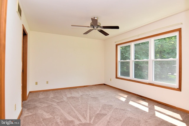 carpeted spare room featuring a wealth of natural light and ceiling fan